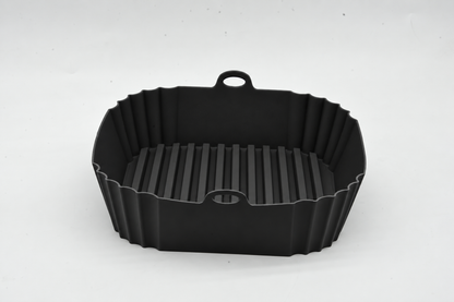 Front view of a black square silicone air fryer liner with ridges and lifting handles